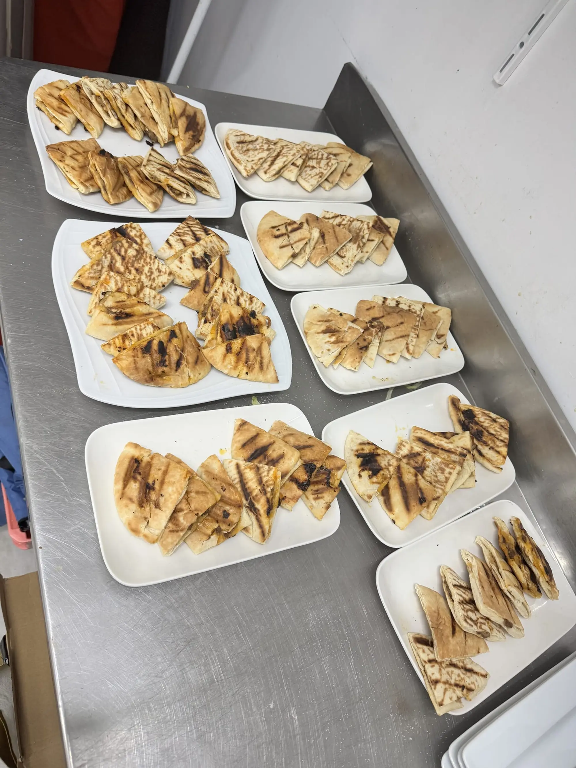 Assiettes de triangles de pain farcis et grillés, alignées sur un plan de travail inox