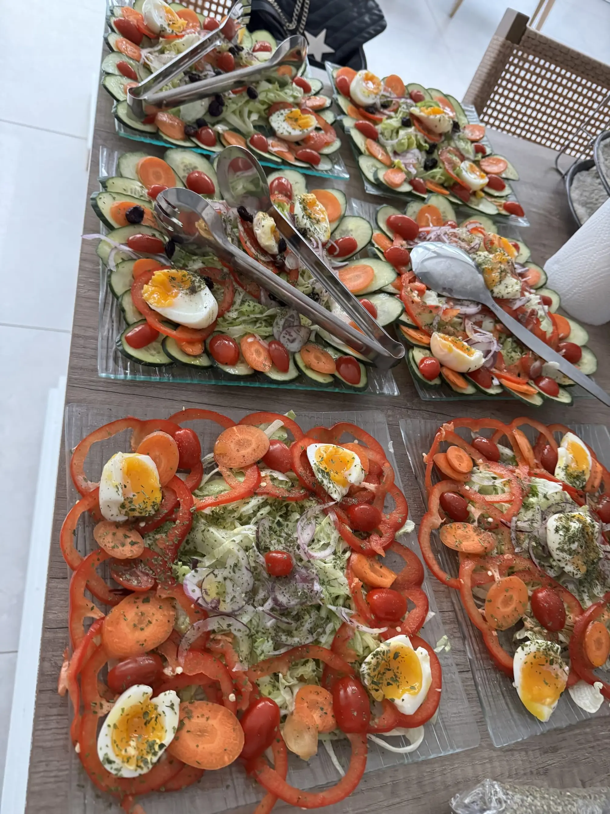 Plateaux de salades composées, tomates, concombres, œufs et carottes, dressés sur une table en bois