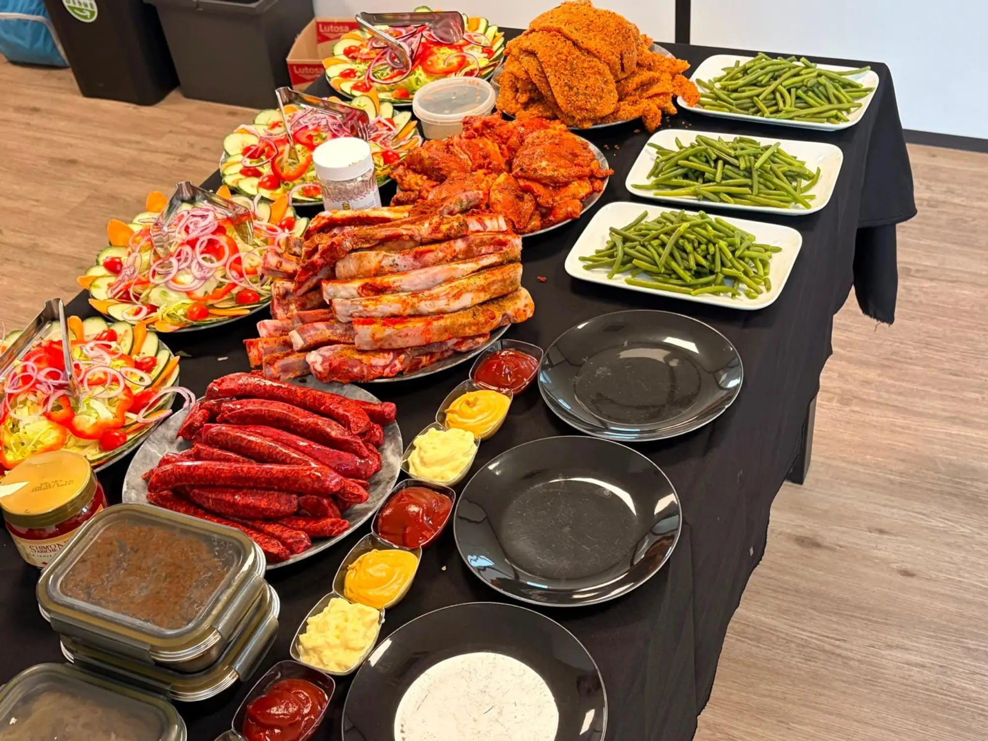 Table de buffet : grandes salades composées, merguez, côtes d’agneau marinées, poulet épicé, schnitzels panés et haricots verts