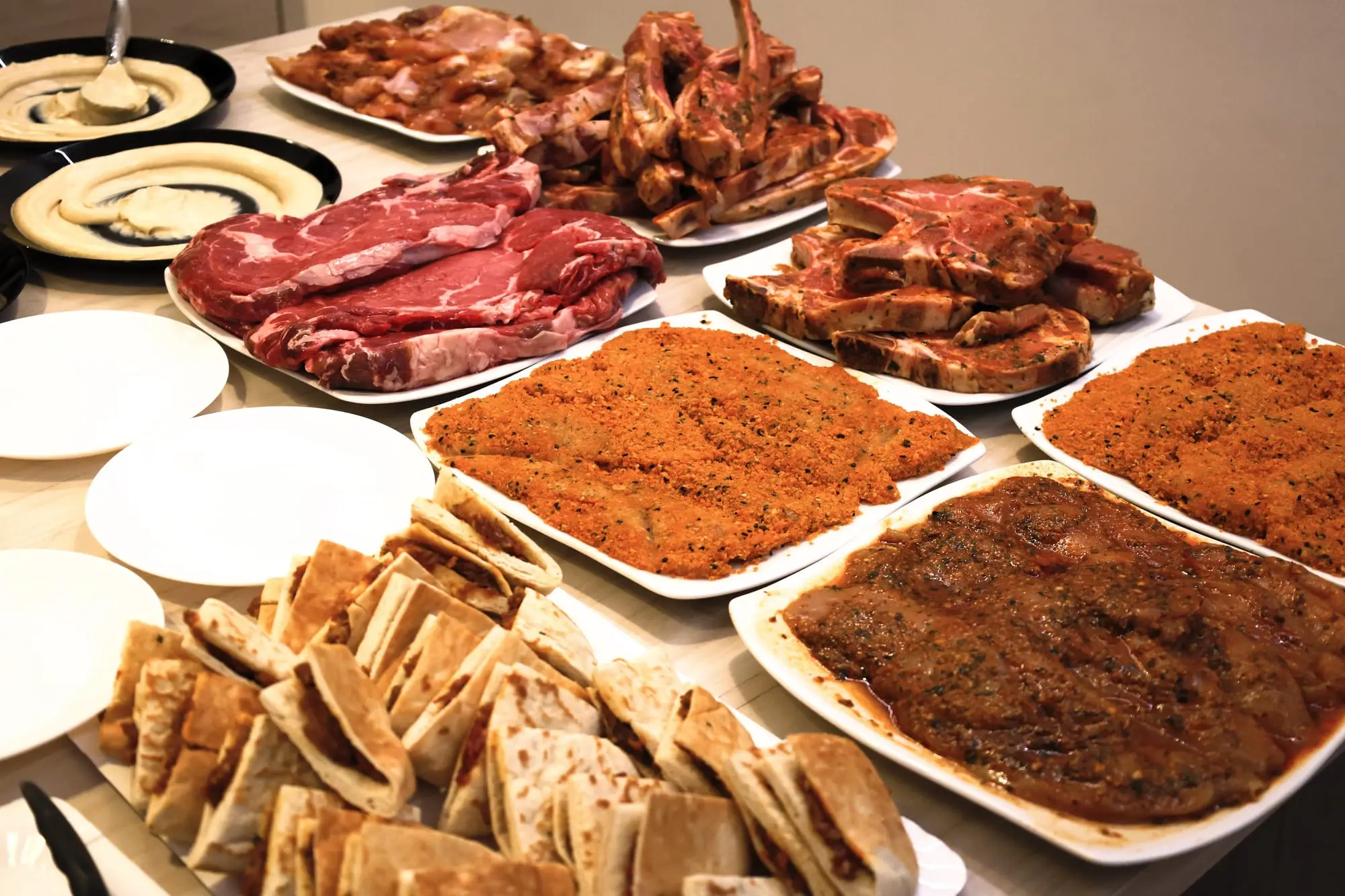 Buffet avec entrecôtes crues, schnitzels panés, pains grillés et houmous
