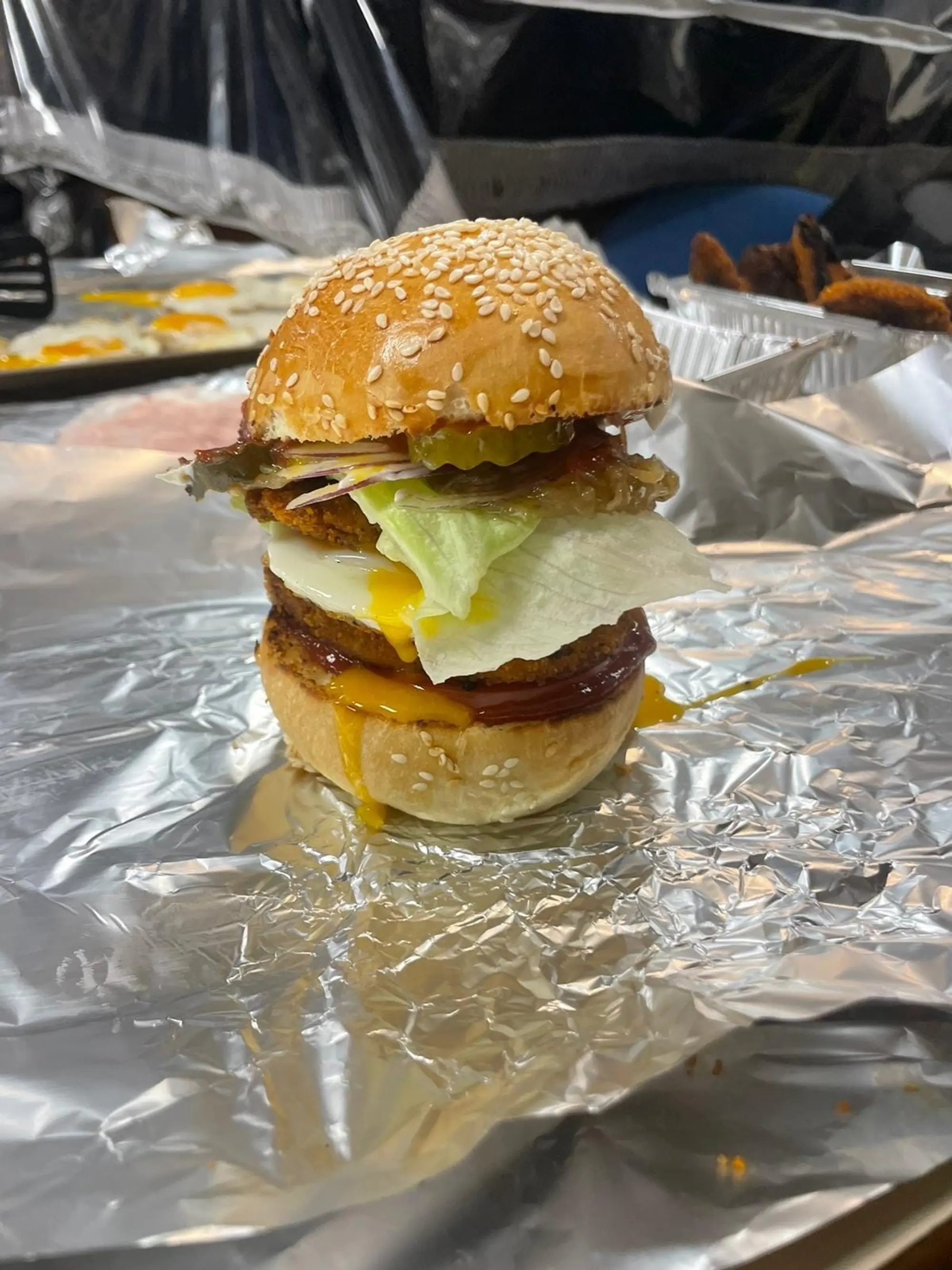 Burger au steak et à l’œuf au plat, tenu dans du papier aluminium