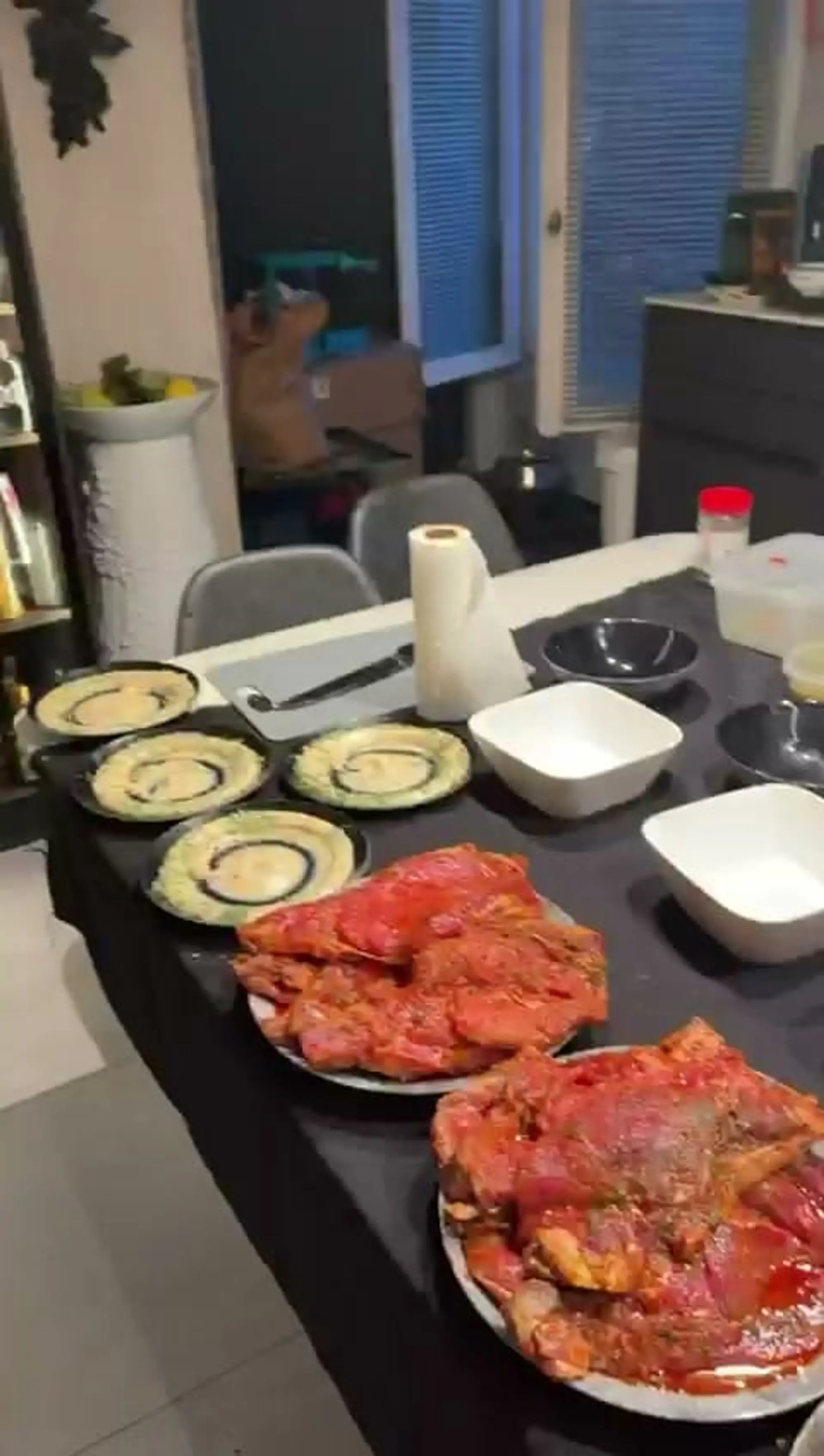 Plats de viandes marinées et assiettes de houmous dressés sur une table noire