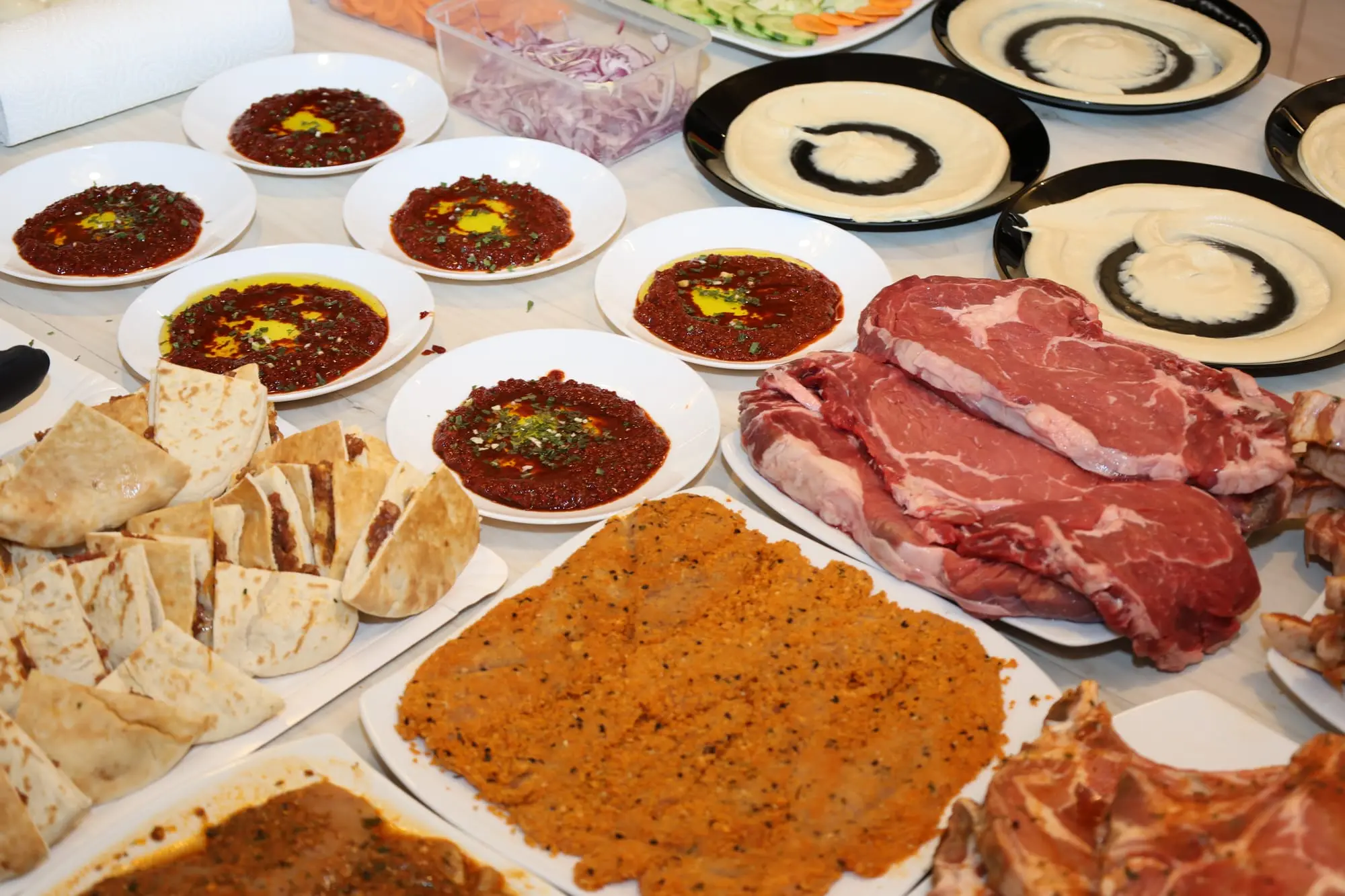 Table de service : entrecôtes, schnitzels, pains et coupelles de houmous