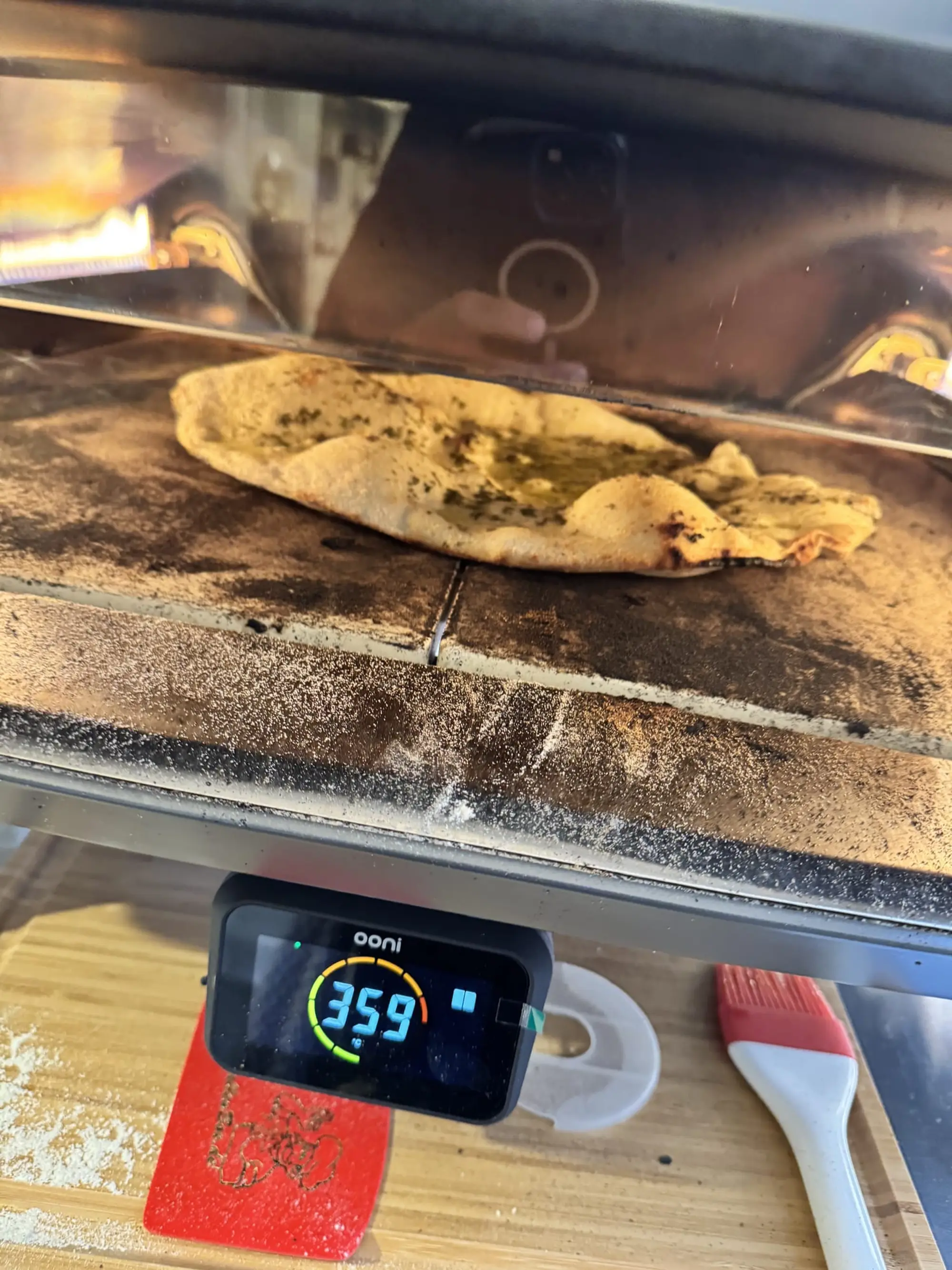 Galette en cuisson dans un four à pizza, thermomètre affichant la température au premier plan