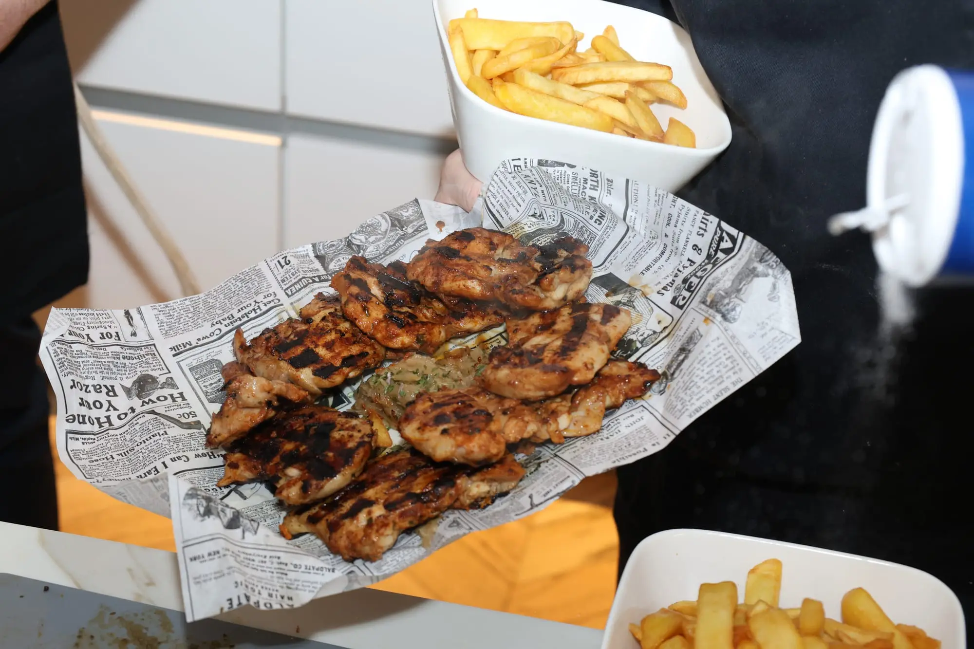 Grillade servie dans un papier journal avec des frites