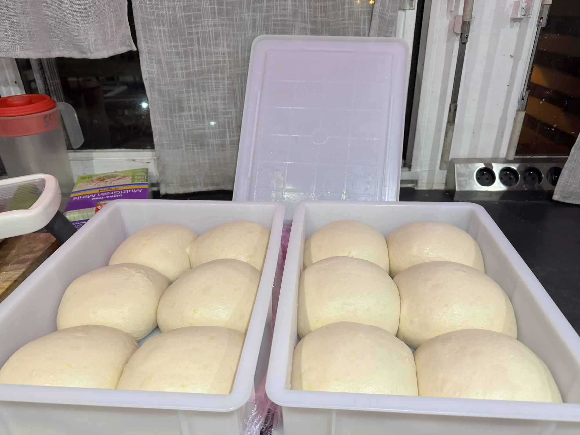 Bacs de pâtons de pizza en cours de pousse, dans une cuisine