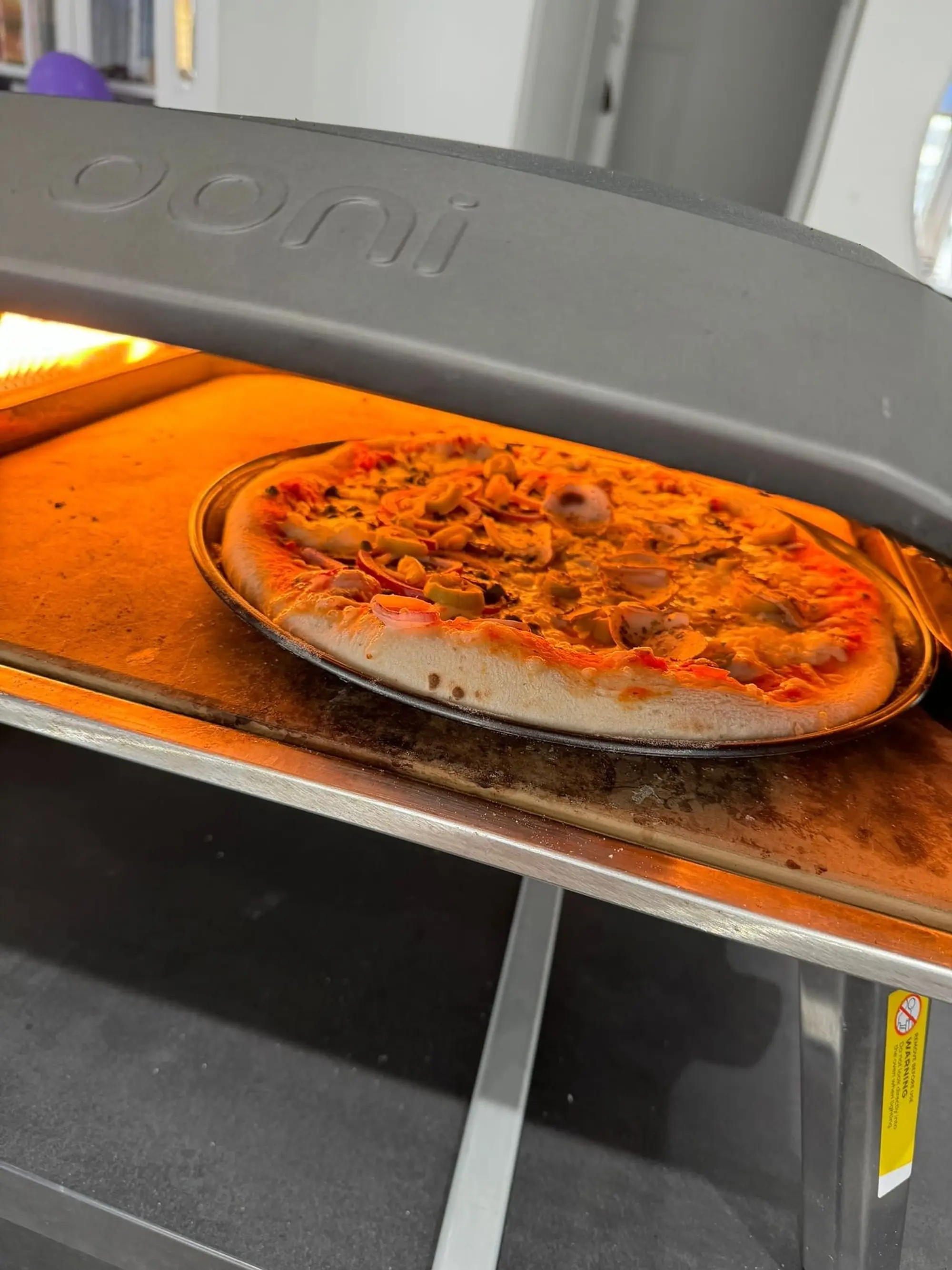 Pizza en cuisson dans un four à pizza, flamme visible