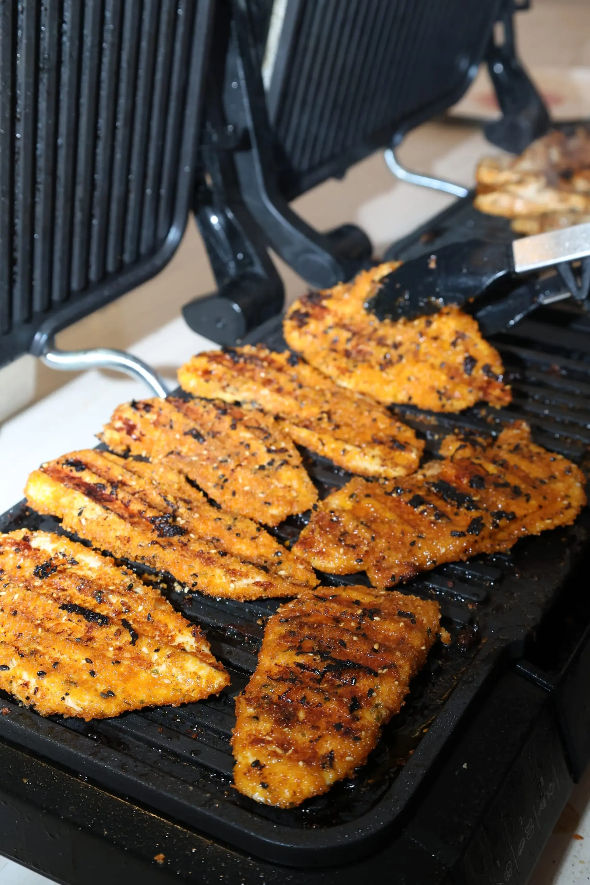 Blancs de poulet marinés en train de griller, marqués par les rainures du gril