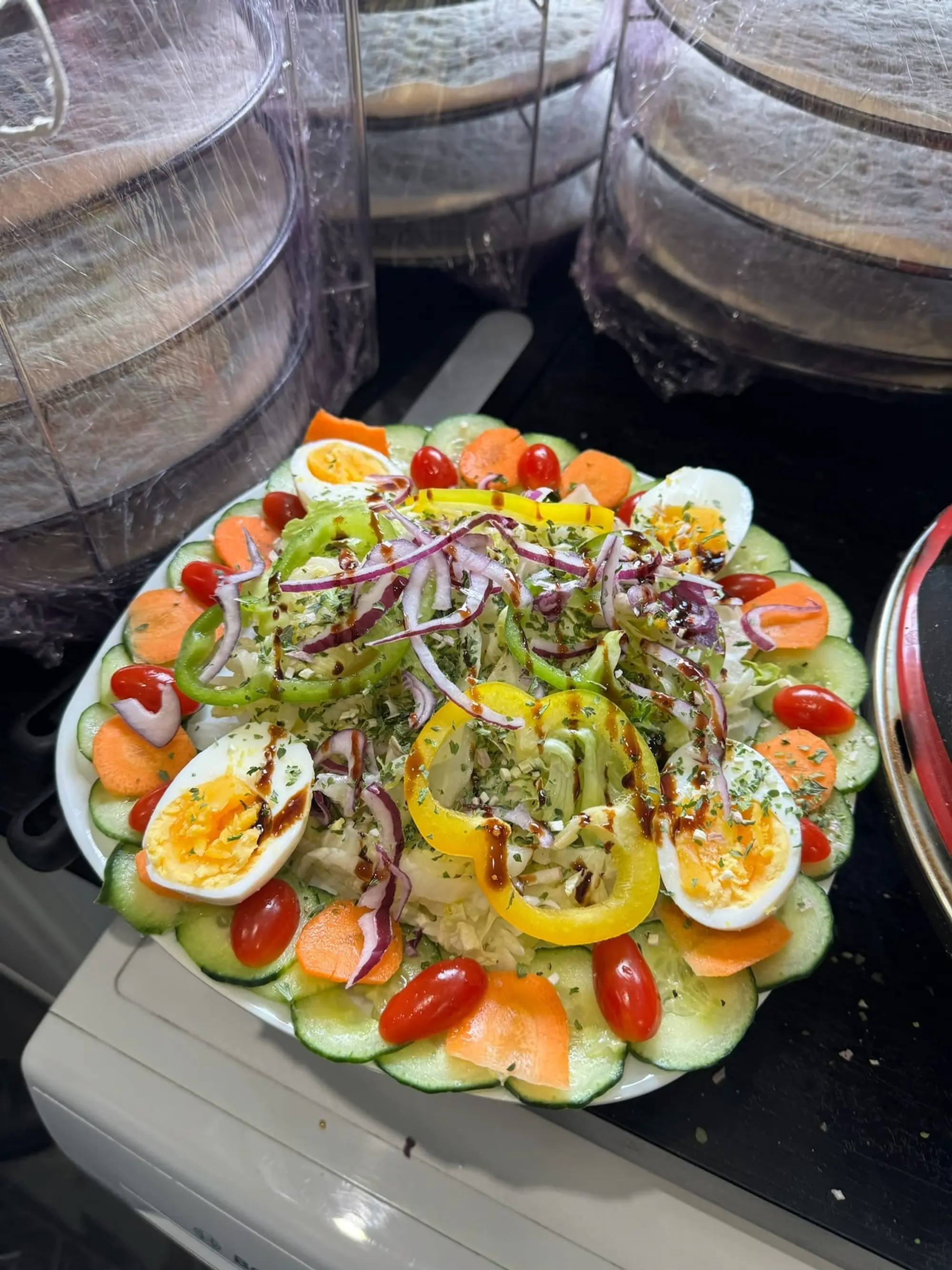 Grande salade composée dressée avec œufs durs, tomates et oignons rouges