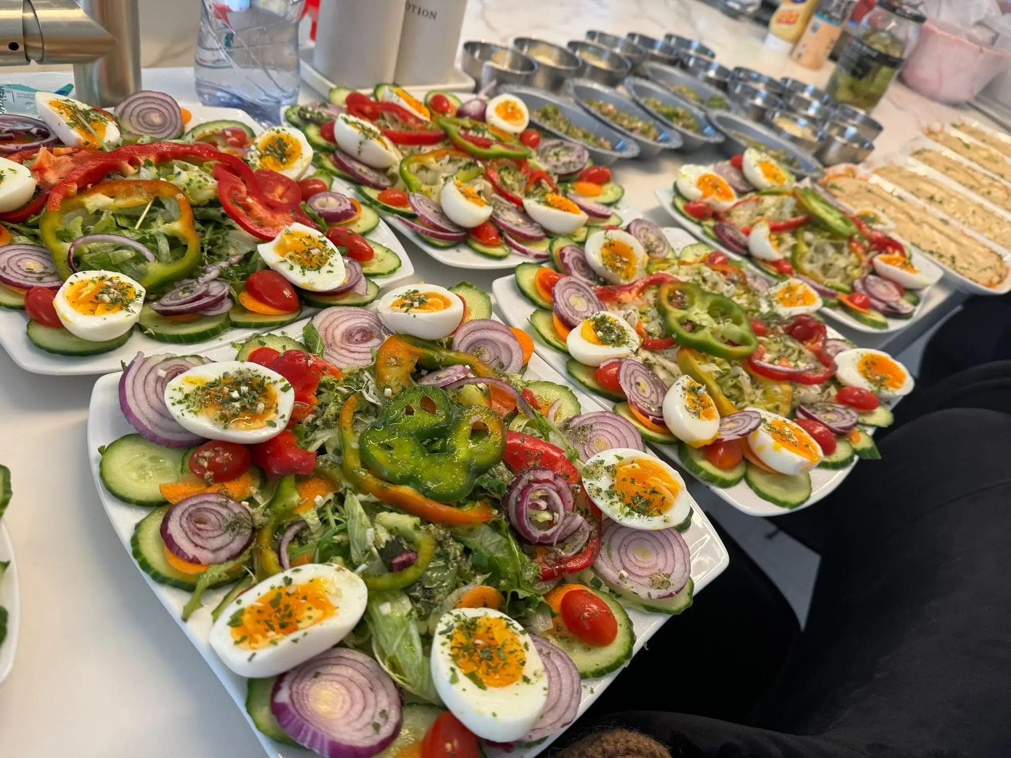 Plusieurs assiettes de salades composées avec œufs, poivrons, oignons rouges et tomates cerises