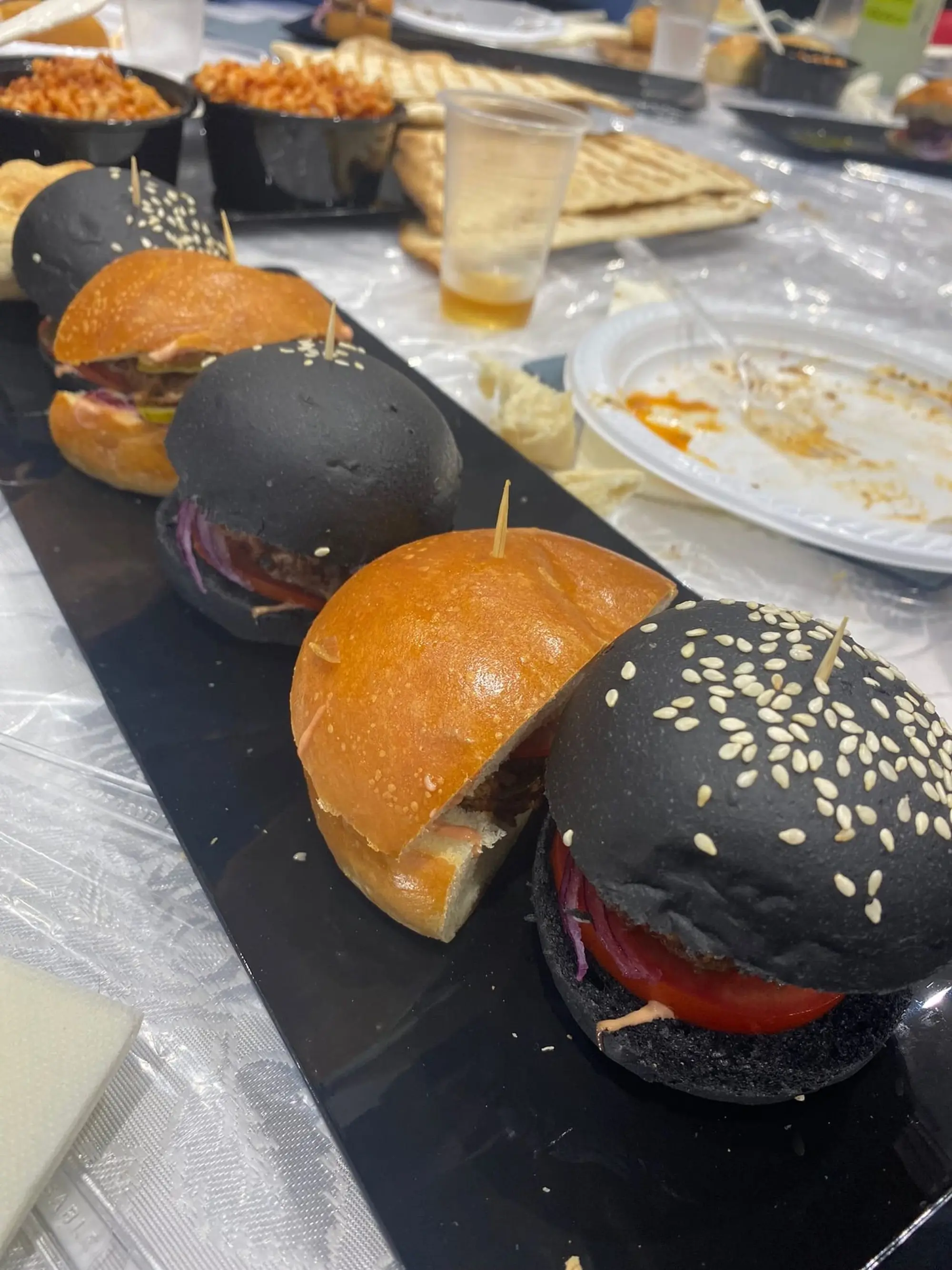 Alignement de mini-burgers avec pains briochés dorés et pains noirs au sésame